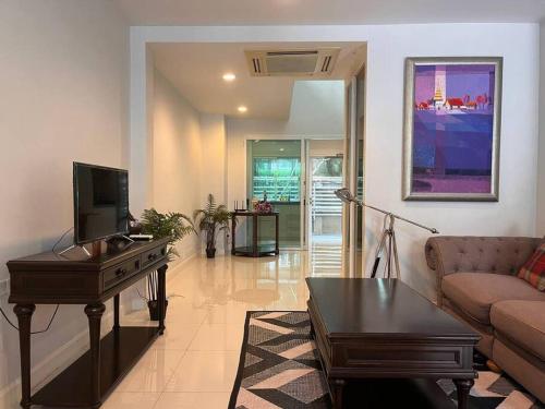 a living room with a couch and a desk with a television at 3BR Sukhumvit Townhouse, close to Emsphere and BTS MRT in Bangkok