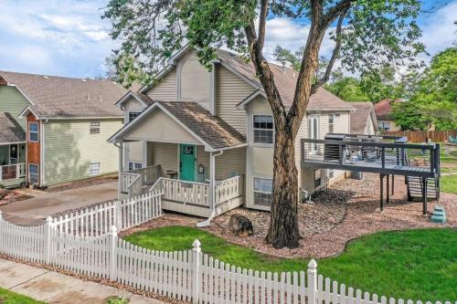 a white fence in front of a house with a tree at Redwood Haus Premier Spot Hot Tub BBQ in Colorado Springs
