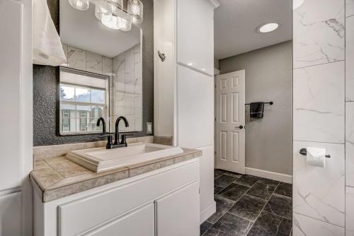 a white bathroom with a sink and a mirror at Redwood Haus Premier Spot Hot Tub BBQ in Colorado Springs