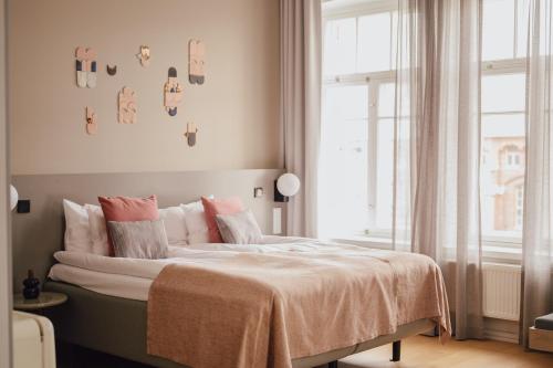 a bedroom with a bed with pink pillows and a window at The Folks Hotel Konepaja in Helsinki