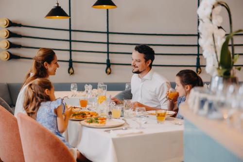 a family sitting at a table in a restaurant at Hotel Linea Mare in Pobierowo