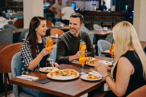 a group of people sitting around a table eating food at Hotel Linea Mare in Pobierowo