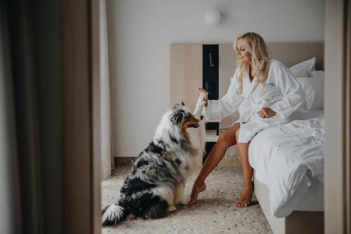a woman sitting on a bed petting a dog at Hotel Linea Mare in Pobierowo