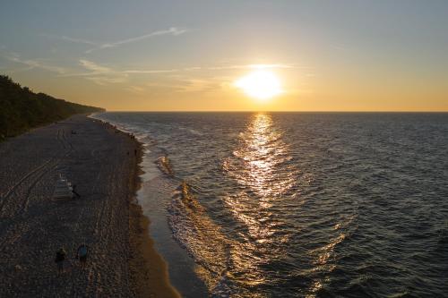a sunset over the ocean with people on the beach at Hotel Linea Mare in Pobierowo