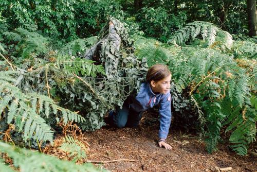 a little girl is kneeling on the ground next to plants at Sani Beach in Sani Beach