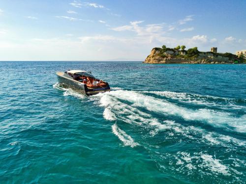 a boat in the water with a small island at Sani Beach in Sani Beach