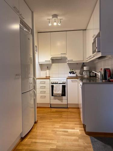 a kitchen with white appliances and a wooden floor at Downtown minimalist apartment with balcony 59m2 in Turku