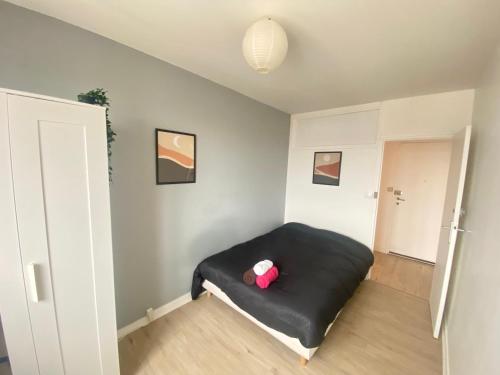 Cette chambre comprend un lit noir avec un oreiller rouge. dans l'établissement Au dessus du jardin - 185, à Sotteville-lès-Rouen