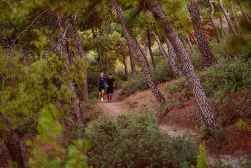 two people walking on a trail through a forest at Porto Sani in Sani Beach