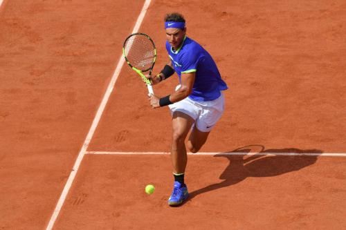 a man holding a tennis racket on a tennis court at Porto Sani in Sani Beach