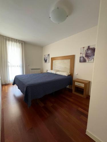 a bedroom with a bed and a wooden floor at Margas Golf Apartment in Sabiñánigo