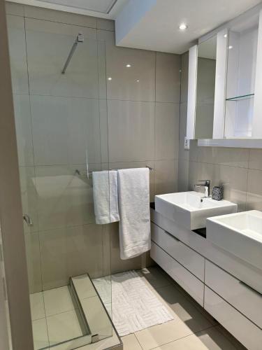 a bathroom with a glass shower and a sink at Lofty-Space in Gaborone