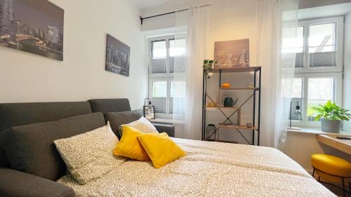 a living room with a bed with yellow pillows at Apartamenty Kopernika 10 in Frombork