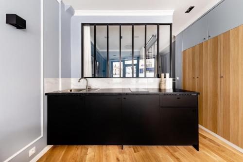 une cuisine avec un évier et une grande fenêtre dans l'établissement Suite Notre Dame 1 Bedroom, à Paris