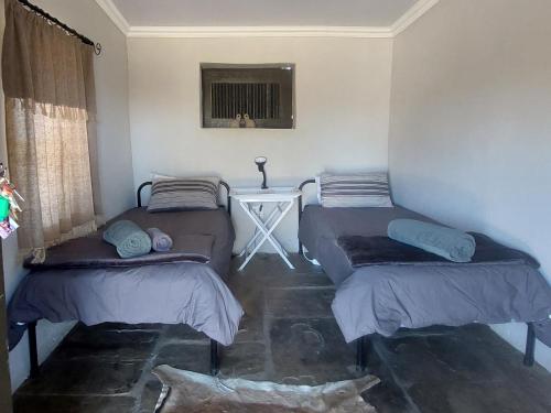 2 Einzelbetten in einem Zimmer mit einem Tisch in der Unterkunft Bundu Camp in Heilbron