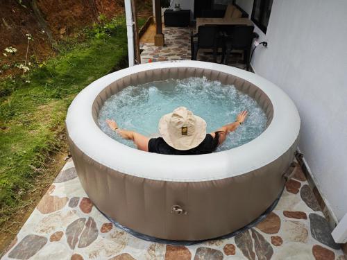 a person in a jacuzzi tub in a backyard at Villa Namaste - Cabaña Albores in Curití
