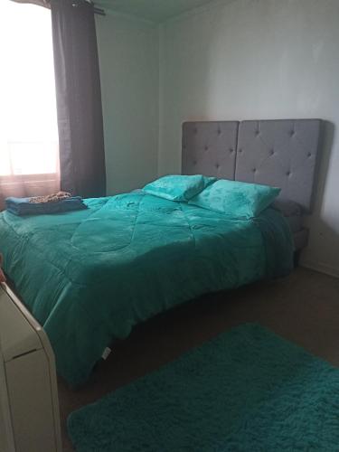 a bedroom with a bed with a green comforter and a window at Terminal Dpto Estación Central Equipado in Santiago