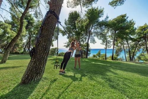 two women standing next to a tree in a park at Sani Club in Sani Beach