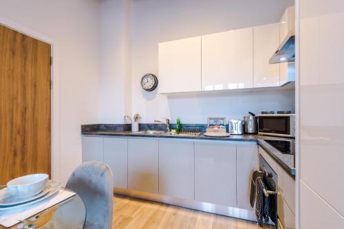 a kitchen with white cabinets and a counter top at Meadow Mill Apartments by Staycay in Heaton Norris