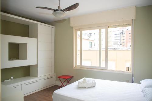 a bedroom with a white bed and a window at Entre Parque Moinhos e Country Club POA ZG6320 in Porto Alegre