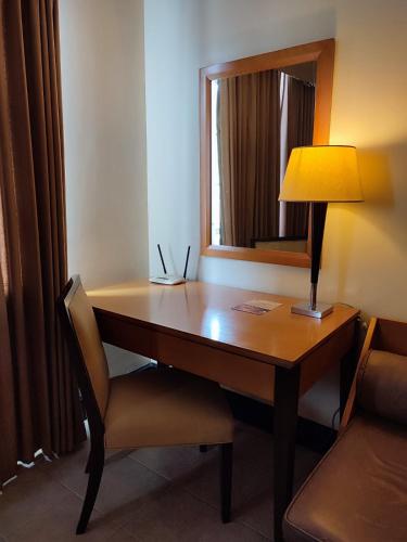 a desk with a lamp and a chair in a room at PonteFino Hotel in Batangas City