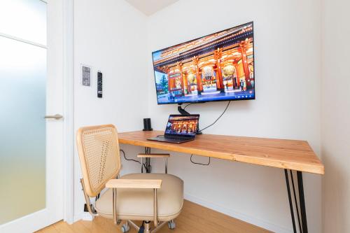 a desk with a laptop and a monitor on a wall at Zen Home AKABANE in Tokyo