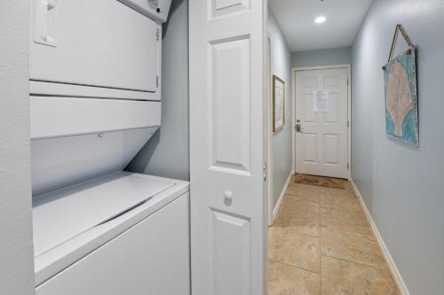 a hallway with a white refrigerator and a door at Grand Caribbean East 207 By Pkrm in Pensacola