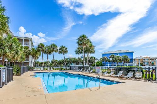a swimming pool with chairs and palm trees at Grand Caribbean East 207 By Pkrm in Pensacola