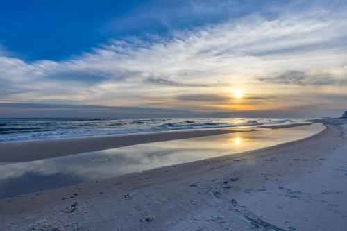 a sunset on a beach with the sun reflecting in the water at Grand Caribbean East 207 By Pkrm in Pensacola