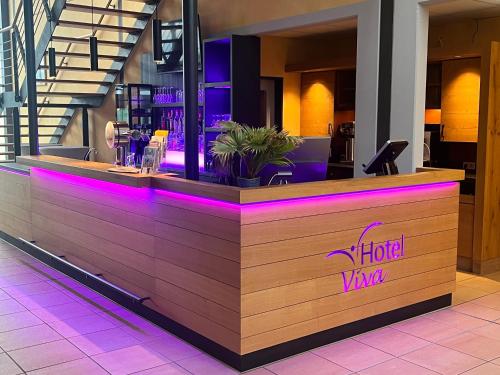 a bar in a restaurant with purple lighting at Hotel Viva Bröckel in Bröckel