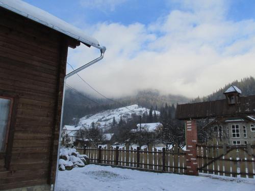 a house with a fence and a snowy mountain at Kryvorizka Palanka in Mykulychyn