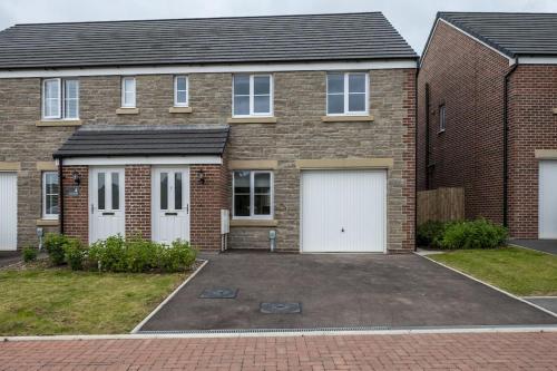 a brick house with two white garage doors at Cosy 3 Bed Near Beaches, Cardiff & Brecon Beacons in Coity