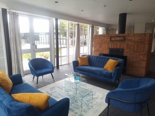 a living room with blue couches and a fireplace at See You There Accommodation in Centurion
