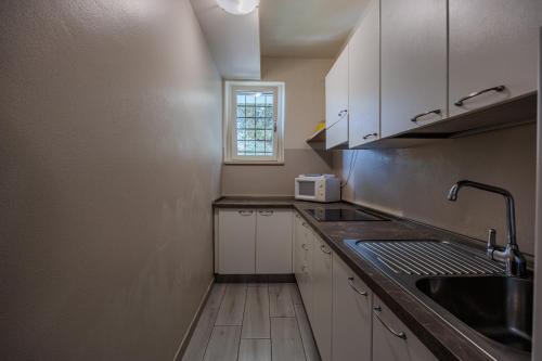 a kitchen with white cabinets and a sink and a window at Residence San Michele in Costermano sul Garda