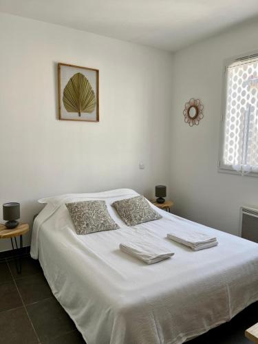 une chambre avec un lit blanc avec deux serviettes dessus dans l'établissement Charmante maison vue garrigue avec piscine, à Lapalme