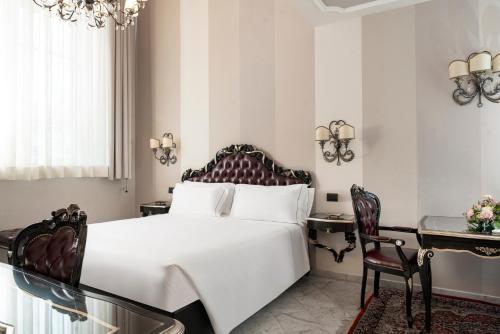 a bedroom with a large white bed and a desk at Grand Hotel di Parma | UNA Esperienze in Parma