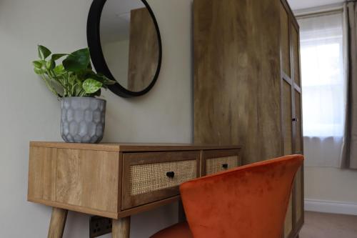 a mirror on top of a wooden dresser with a orange chair at Orange Grove Hotel & Gardens in Southampton