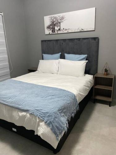a bedroom with a large bed with a gray headboard at iThusi in Mbabane