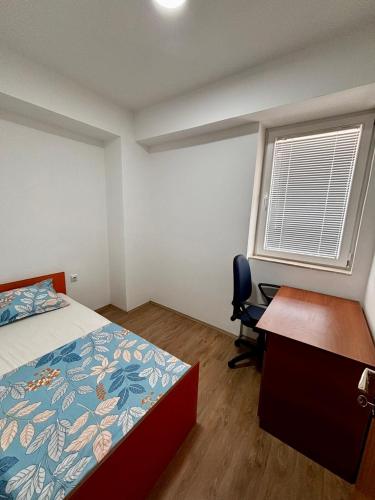 a bedroom with a bed and a desk and a window at Central Comfort- Fresh & Modern in Bitola