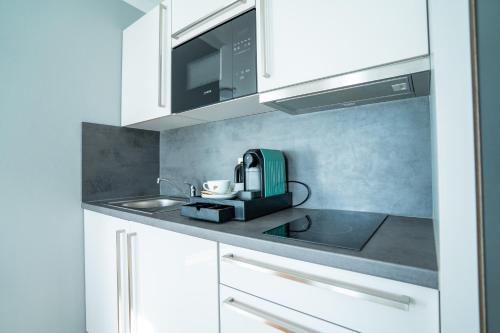 a kitchen with white cabinets and a green appliance at Boardinghouse City Home in Bielefeld