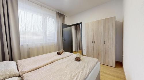 a bedroom with two beds and a large window at SALAN Apartman Galanta in Galanta