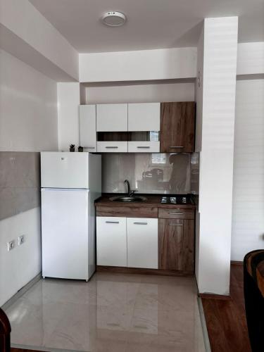 a kitchen with a white refrigerator and wooden cabinets at Central Comfort- Fresh & Modern in Bitola