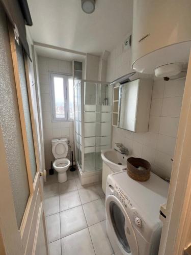une salle de bain avec machine à laver et toilettes dans l'établissement Charmant appartement aux Portes de Paris - 2PAX, à Saint-Ouen