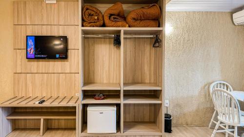 a room with a book shelf with a tv and bread at Hotel Pousada Ald' Mama in Gramado
