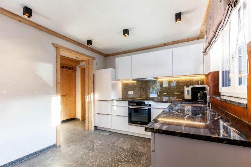 a kitchen with white cabinets and a black counter top at Casa de Wisa in Gaschurn