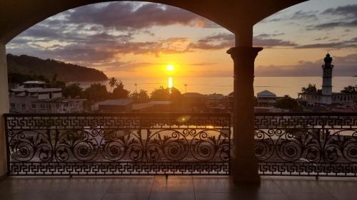 a sunset from a balcony with a view of a lighthouse at Grande maison avec vue sur la mer in Mtsamboro