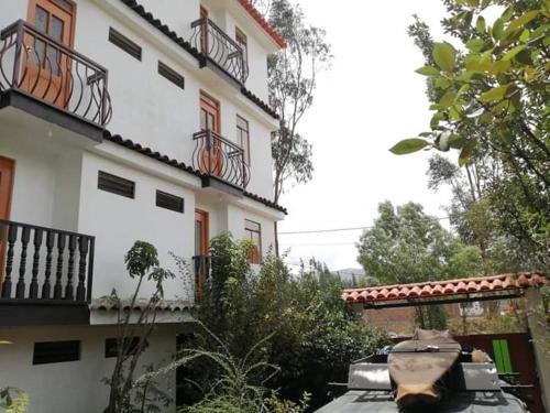 a white building with a car parked in front of it at Hostal Casa del Montañista in Huaraz