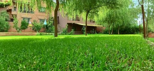 a building with a field of green grass and trees at Country homes in Ourika