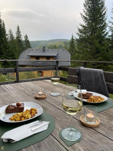 Una mesa con dos platos de comida y copas de vino. en Almhütte-Flattnitz, en Flattnitz