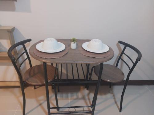 a wooden table with two chairs and two hats on it at Saekyung Condominium in Basbas